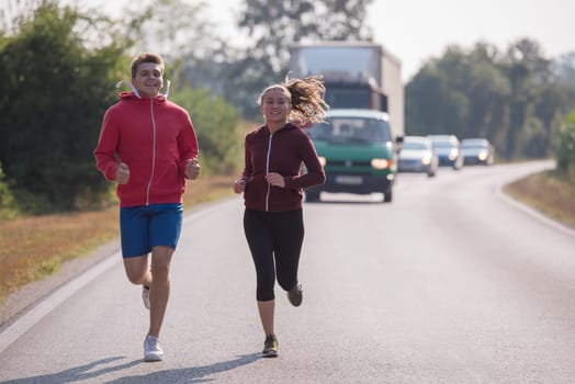 young couple enjoying in a healthy lifestyle while jogging along a country road, exercise and fitness concept