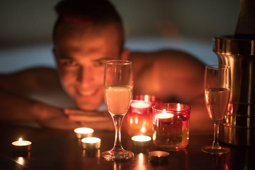 young handsome man enjoys relaxing in the jacuzzi with candles and champagne at luxury resort spa