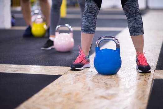 group of healthy young athletes doing exercises with kettlebells at cross fitness studio