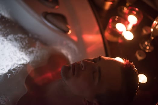 young handsome man enjoys relaxing in the jacuzzi with candles and champagne at luxury resort spa