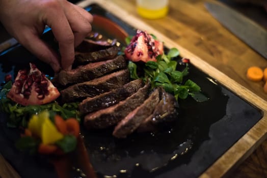 closeup of Chef hands in hotel or restaurant kitchen serving beef steak with vegetable decoration