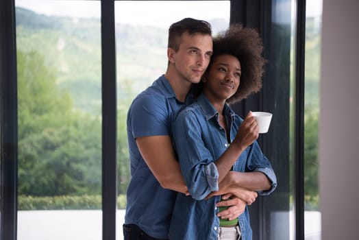 romantic happy young multiethnic couple enjoying morning coffee by the window in their luxury home