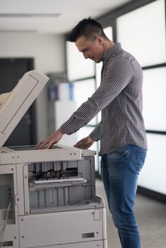 young business man copy documents on copy machine at modern startup office interior, casual clothes