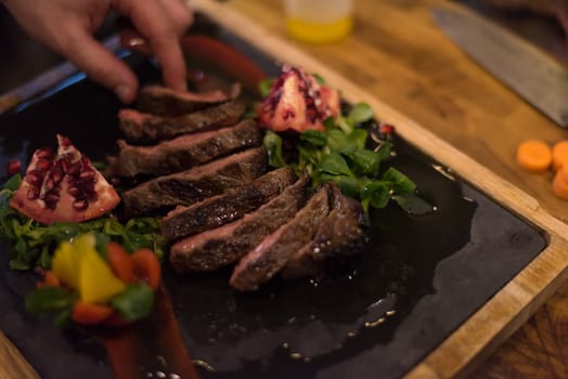 closeup of Chef hands in hotel or restaurant kitchen preparing beef steak with vegetable decoration