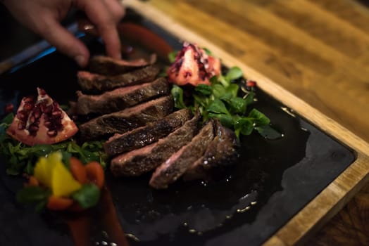 closeup of Chef hands in hotel or restaurant kitchen serving beef steak with vegetable decoration
