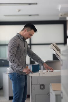 young business man copy documents on copy machine at modern startup office interior, casual clothes