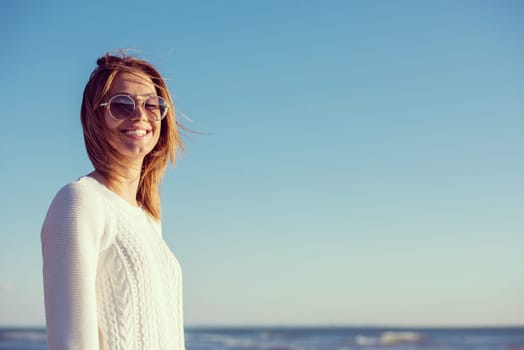 Young woman on the beach. The girl enjoying the warm autumn day. Portrait of beautiful girl near the water