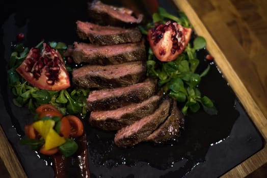 Juicy slices of grilled steak  with vegetables on a wooden board