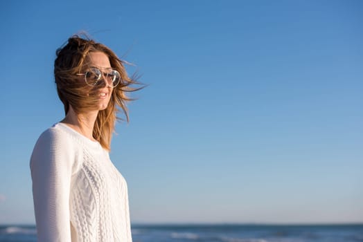 Young woman on the beach. The girl enjoying the warm autumn day. Portrait of beautiful girl near the water