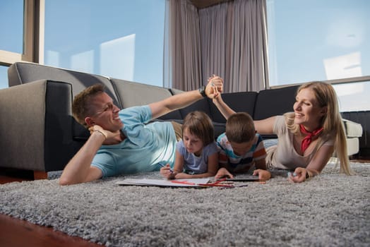 Happy Young Family Playing Together at home on the floor using a tablet and a children's drawing set