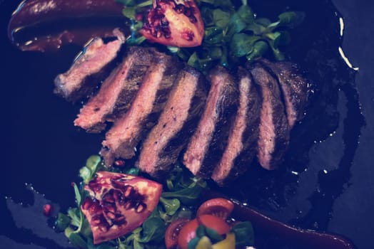 Juicy slices of grilled steak  with vegetables on a wooden board