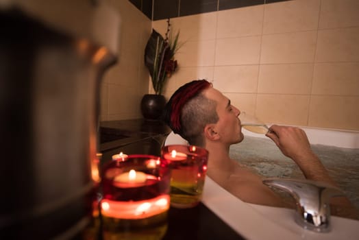 young handsome man enjoys relaxing in the jacuzzi with candles and champagne at luxury resort spa