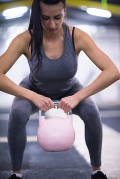 young  woman athlete exercise with fitness kettlebell at cross fitness gym