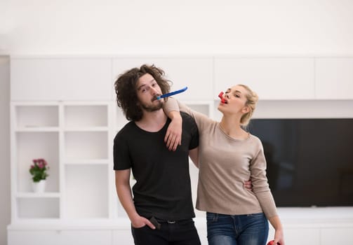 Young happy couple in party hats blowing in whistle isolated on a white background