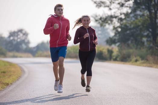 young couple enjoying in a healthy lifestyle while jogging along a country road, exercise and fitness concept
