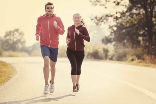 young couple enjoying in a healthy lifestyle while jogging along a country road, exercise and fitness concept