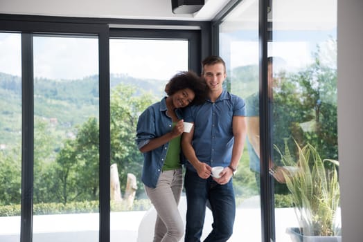 romantic happy young multiethnic couple enjoying morning coffee by the window in their luxury home