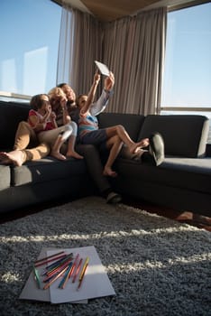 happy couple spending time with kids using tablet computer on sofa at home