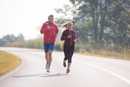 young couple enjoying in a healthy lifestyle while jogging along a country road, exercise and fitness concept