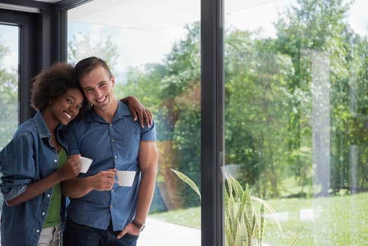 romantic happy young multiethnic couple enjoying morning coffee by the window in their luxury home
