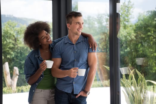 romantic happy young multiethnic couple enjoying morning coffee by the window in their luxury home
