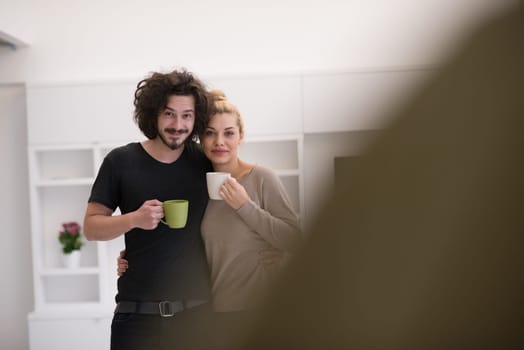 Portrait of a happy young beautiful couple hugging and drinking coffee in their new home