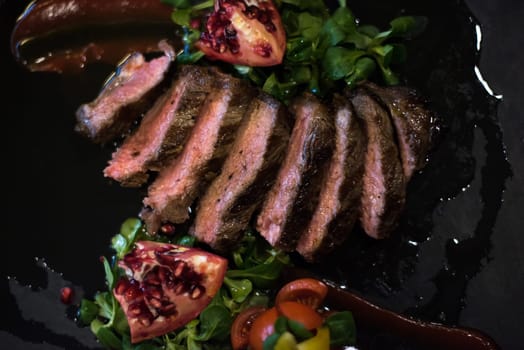 Juicy slices of grilled steak  with vegetables on a wooden board