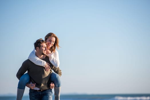 Men Giving Piggy Back Rides to his girlfriend At Sunset By The Sea, autumn time