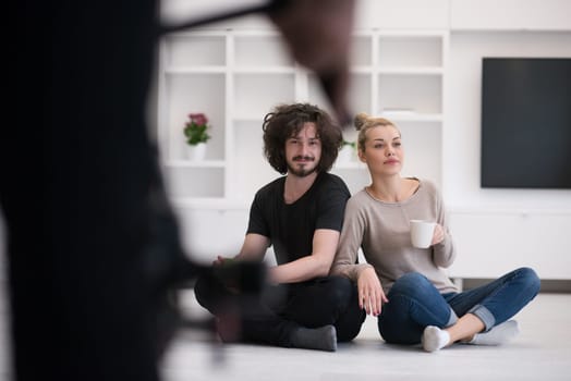 portrait of young happy beautiful couple sitting on the floor and drinking coffee in their new home