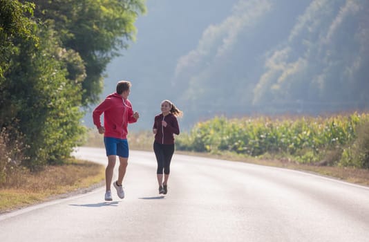 young couple enjoying in a healthy lifestyle while jogging along a country road, exercise and fitness concept