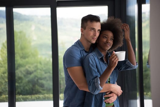 romantic happy young multiethnic couple enjoying morning coffee by the window in their luxury home