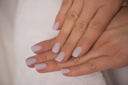 Beautiful fingers with french manicure on the towel. Manicure in a beauty salon.