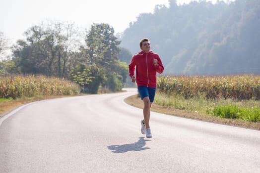 young man enjoying in a healthy lifestyle while jogging along a country road, exercise and fitness concept