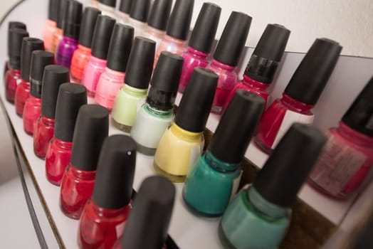 Set of different bottles of nail polish in the shelf in the beauty salon