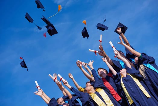 high school students graduates tossing up hats over blue sky.
