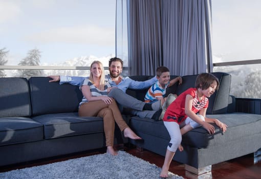 happy couple spending time with kids using tablet computer on sofa at home