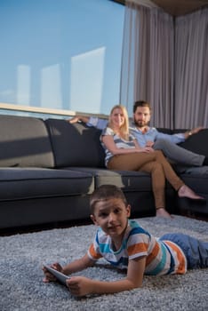 happy couple spending time with kids using tablet computer on sofa at home