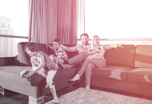 happy couple spending time with kids using tablet computer on sofa at home