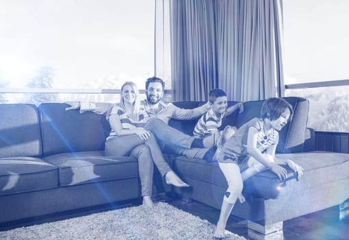 happy couple spending time with kids using tablet computer on sofa at home