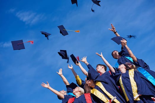 high school students graduates tossing up hats over blue sky.