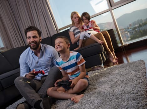 Happy family. Father, mother and children playing a video game Father and son playing video games together on the floor