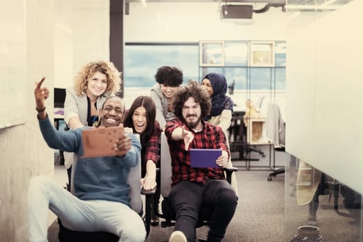 multiethnics startup business team of software developers having fun while racing on office chairs,excited diverse employees laughing enjoying funny activity at work break, creative friendly workers playing game together