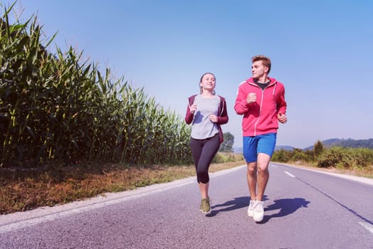 young couple enjoying in a healthy lifestyle while jogging along a country road, exercise and fitness concept