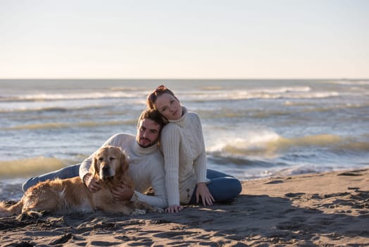 Couple With A Dog enjoying time  together On The Beach at autumn day