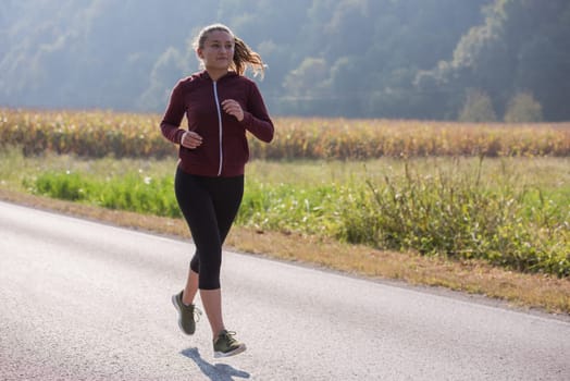 young woman enjoying in a healthy lifestyle while jogging along a country road, exercise and fitness concept