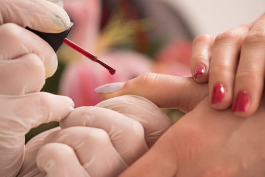 Woman hands receiving a manicure in beauty salon. Nail filing. Close up, selective focus.