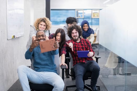 multiethnics startup business team of software developers having fun while racing on office chairs,excited diverse employees laughing enjoying funny activity at work break, creative friendly workers playing game together