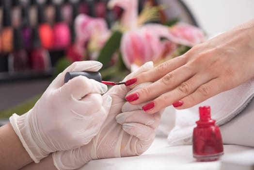 Woman hands receiving a manicure in beauty salon. Nail filing. Close up, selective focus.