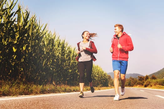 young couple enjoying in a healthy lifestyle while jogging along a country road, exercise and fitness concept