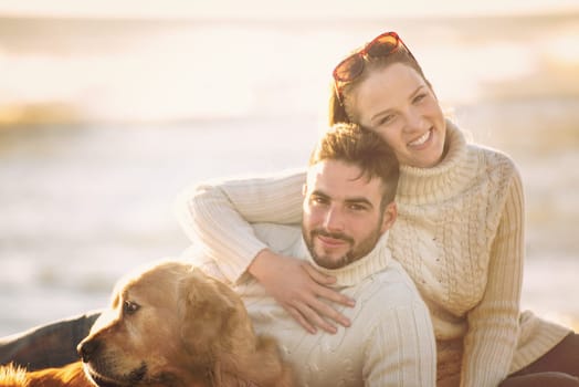 Couple With A Dog enjoying time  together On The Beach at autumn day